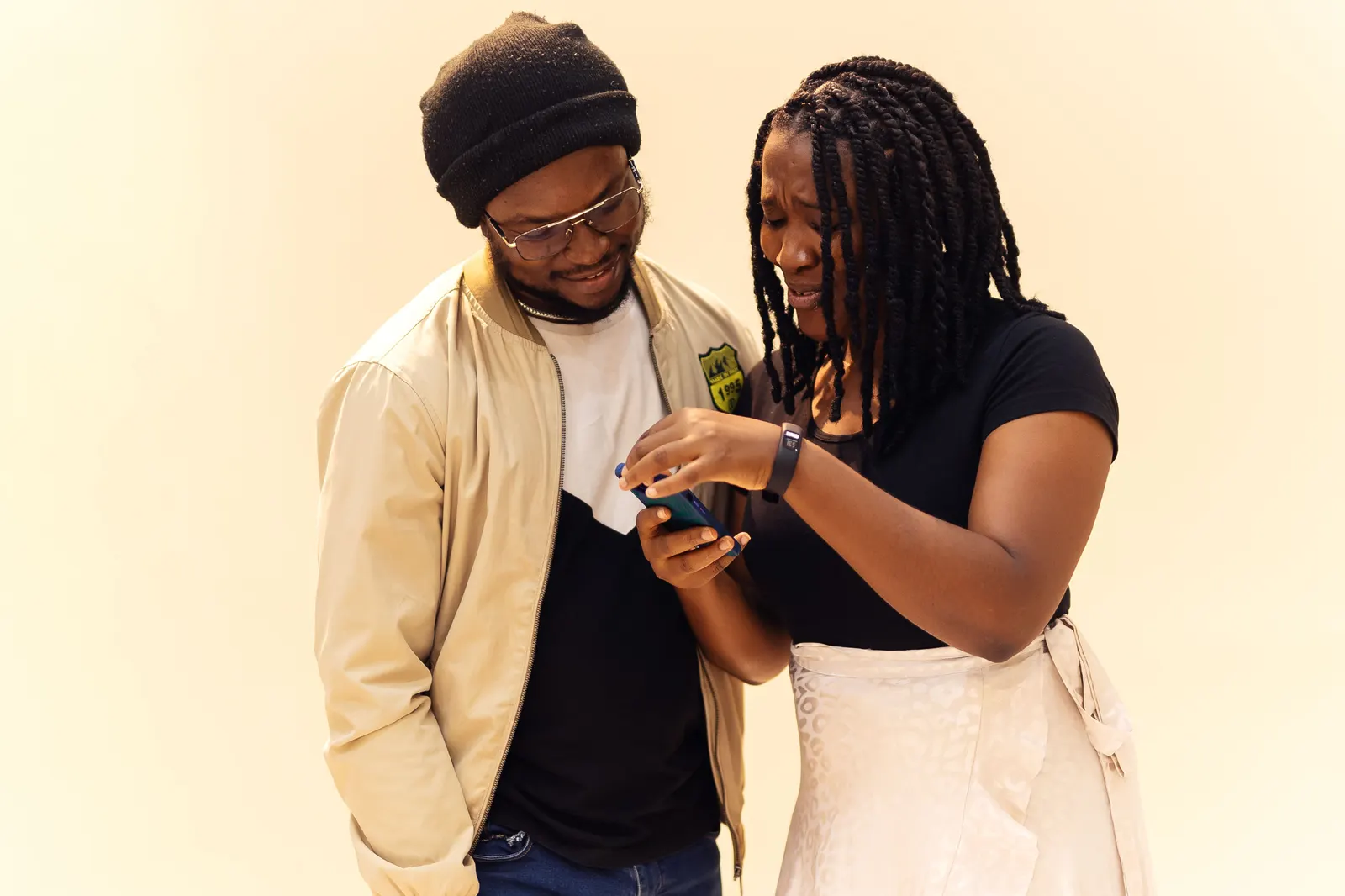 Friends in Lagos smiling together over a phone